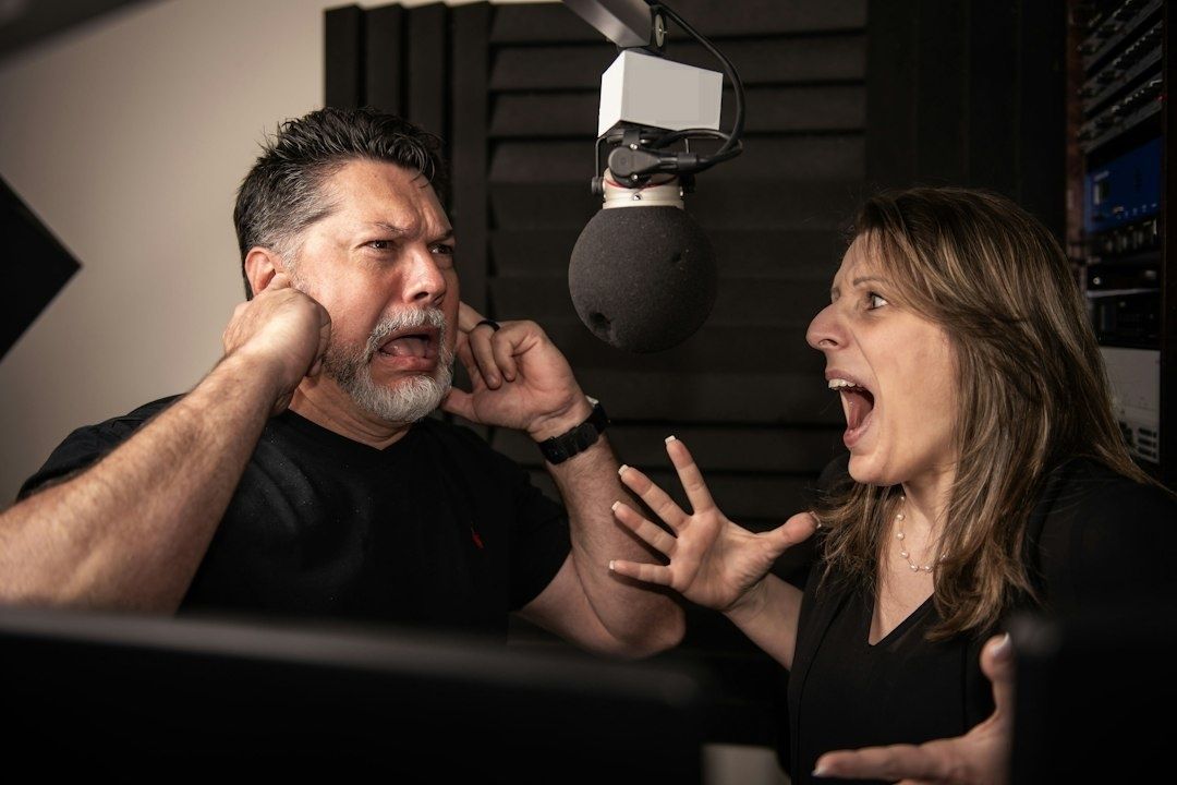 Twee presentatoren discussiëren fel bij een microfoon in een radiostudio